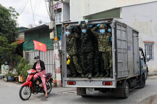جنود فيتناميون ينظرون من شاحنة وهم يسلمون الطعام في مناطق مغلقة مشددة وسط جائحة فيروس كورونا (كوفيد-19) في هوشي منه، فيتنام، 24 أغسطس 2021 - سبوتنيك عربي