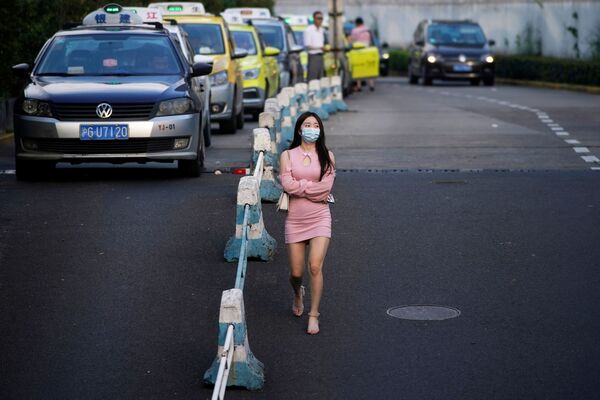 امرأة ترتدي قناعًا واقيًا تمشي في أحد الشوارع، بعد الإعلان عن حالات الإصابة جديدة بمرض فيروس كورونا (كوفيد-19) في شنغهاي، الصين  23 أغسطس 2021 - سبوتنيك عربي