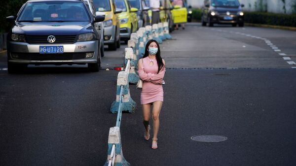 امرأة ترتدي قناعًا واقيًا تمشي في أحد الشوارع، بعد الإعلان عن حالات الإصابة جديدة بمرض فيروس كورونا (كوفيد-19) في شنغهاي، الصين  23 أغسطس 2021 - سبوتنيك عربي