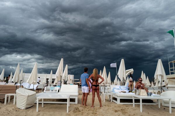 ينظر الناس إلى السحب السوداء أثناء وقوفهم على شاطئ في راماتويل، بالقرب من سان تروبيه، جنوب فرنسا 24 أغسطس 2021 - سبوتنيك عربي