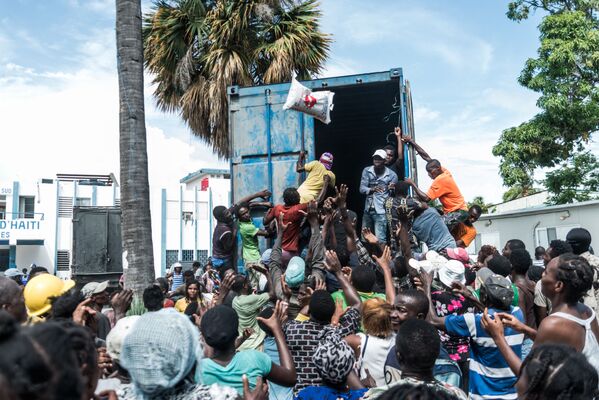 رجل يلقي بكيس أرز وسط حشد من الناس أثناء توزيع الطعام والماء على ضحايا الزلزال في لو كواي، هايتي 20 أغسطس 2021 - سبوتنيك عربي