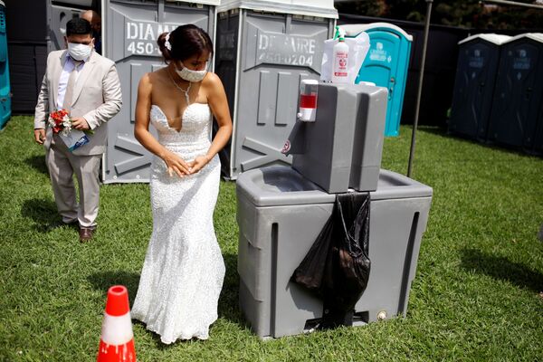 عروس تعقم يديها خلال أول حفل زفاف جماعي منذ ظهور جائحة فيروس كورونا (كوفيد-19) في ليما، بيرو  28 أغسطس 2021 - سبوتنيك عربي