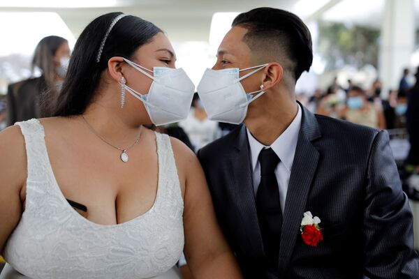 قبلة زوجين حديثين وهما يرتديان كمامة خلال أول حفل زفاف جماعي منذ ظهور جائحة فيروس كورونا (كوفيد-19) في ليما، بيرو  28 أغسطس 2021 - سبوتنيك عربي