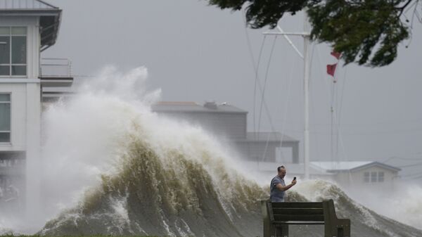 رجل يلتقط صوراً للأمواج العالية على طول شاطئ بحيرة بونتشارترين مع اقتراب إعصار إيدا، في نيو أورلينز 29 أغسطس 2021 - سبوتنيك عربي