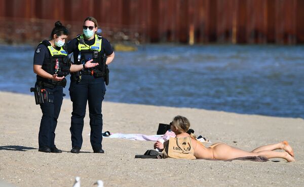 تتحدث الشرطة إلى امرأة تستمتع بطقس الربيع الدافئ بشكل غير معتاد على شاطئ سانت كيلدا في ملبورن،  حيث لا تزال المدينة مغلقة لأنها تكافح سلالة دلتا من فيروس كورونا، أستراليا 2 سبتمبر 2021 - سبوتنيك عربي