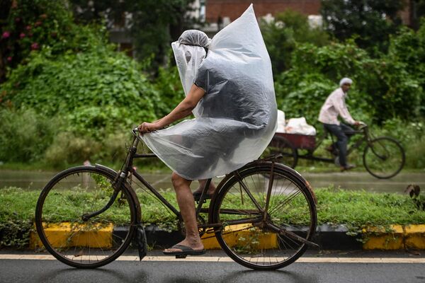 راكب دراجة يغطي نفسه بغطاء بلاستيكي أثناء هطول أمطار غزيرة في فريد آباد، الهند 1 سبتمبر 2021 - سبوتنيك عربي