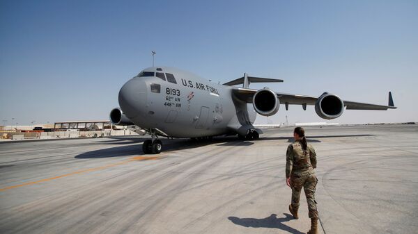 ضابط بالجيش الأمريكي تسير باتجاه طائرة تابعة للقوات الجوية الأمريكية في قاعدة العديد الجوية في الدوحة - سبوتنيك عربي