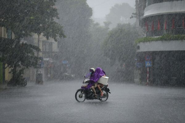سائقي السيارات يركبون دراجة وسط هطول أمطار غزيرة في هانوي، فيتنام 8 سبتمبر 2021 - سبوتنيك عربي