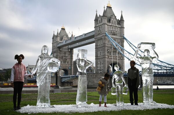 أطفال يقفون أمام منحوتات جليدية تصور أشخاصًا يجمعون المياه من قبل منظمة Water Aid الخيرية، لإظهار هشاشة المياه والتهديد الذي يشكله تغير المناخ، لندن، إنجلترا 15 سبتمبر 2021. - سبوتنيك عربي