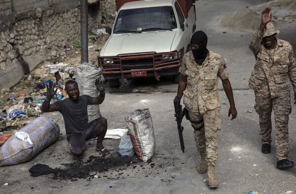 رجل يرفع ذراعيه لإظهار براءته بينما يقوم رجال الشرطة بدوريات في شوارع وسط مدينة بورت أو برنس، حيث أقام السكان حاجزًا احتجاجًا على اتهام الشرطة بقتل رجل أثناء مداهمة، هايتي  22 سبتمبر 2021. - سبوتنيك عربي
