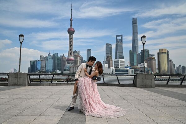 زوجان يقفان خلال جلسة تصوير قبل الزفاف على الكورنيش في بوند على طول نهر هوانغبو في شنغهاي، الصين 24 سبتمبر 2021. - سبوتنيك عربي