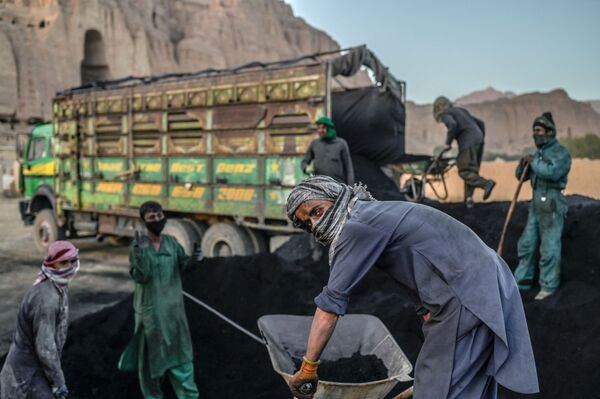 يستعد عمال الهزارة لتحميل الفحم على شاحنة بالقرب من الموقع الذي كان يقف فيه تمثال بوذا، قبل أن تدمره طالبان في مارس 2001، في مقاطعة باميان في 3 أكتوبر 2021. - سبوتنيك عربي