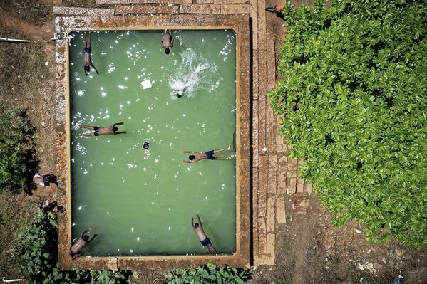 في هذه الصورة الجوية التي التقطت في 4 أكتوبر 2021، يغطس الصبيان في خزان مياه مفتوح في أرض زراعية في ضواحي بنغالور، الهند - سبوتنيك عربي
