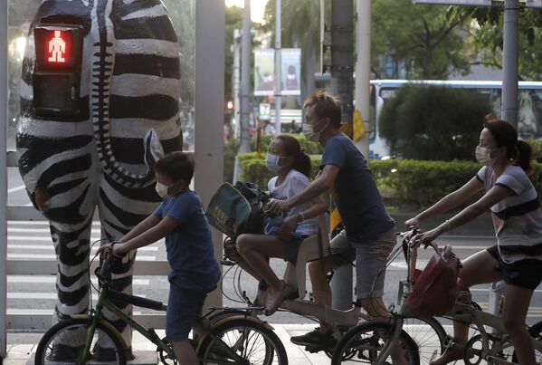 راكبو الدراجات يرتدون كمامات، ينتظرون عند إشارة مرور على شكل حمار وحشي في تايبيه، تايوان 6 أكتوبر 2021 - سبوتنيك عربي