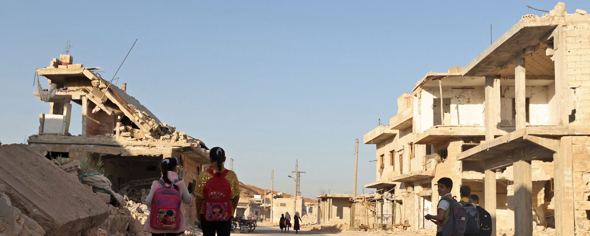 أطفال يمشون بين الأنقاض أثناء حضورهم اليوم الأول من المدرسة في قرية في ريف إدلب شمال غرب سوريا، 9 أكتوبر 2021.  - سبوتنيك عربي, 1920, 29.01.2022