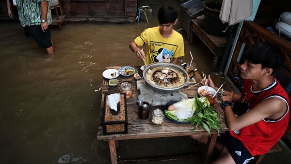 أشخاص يستمتعون بوجبة عشائهم في مقهى تشاو فرايا أنتيك (Chaopraya Antique)، حيث تتدفق مياه الفيضانات من نهر تشاو فرايا إلى المطعم في مقاطعة نونثابوري، شمال بانكوك، 7 أكتوبر 2021 - سبوتنيك عربي