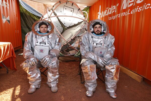 اثنان من رواد الفضاء يجلسان داخل ما يشبه قمرة المركبة الفضائية، أثناء التدريب في موقع يحاكي محطة فضاء في حفرة رمون في متسبي رمون في صحراء النقب جنوب إسرائيل، 10 أكتوبر 2021. - سبوتنيك عربي