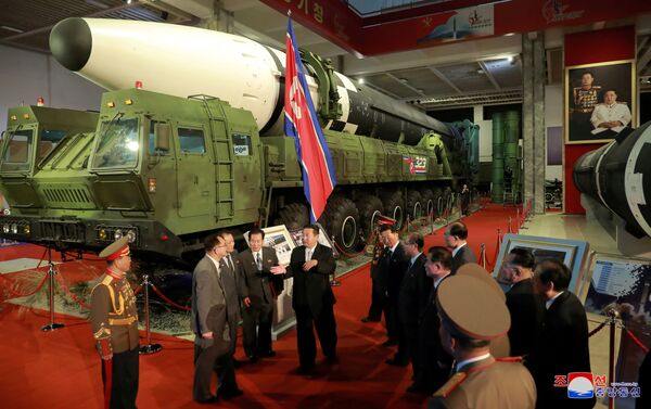 زعيم كوريا الشمالية كيم جونغ أون إلى المسؤولين بجوار الأسلحة والمركبات العسكرية المعروضة، بما في ذلك الصواريخ الباليستية العابرة للقارات (ICBM)، في معرض تطوير الدفاع، في بيونغ يانغ، كوريا الشمالية، 12 أكتوبر 2021 . - سبوتنيك عربي