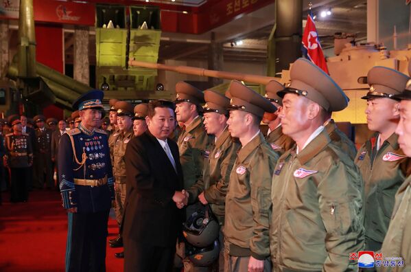 زعيم كوريا الشمالية كيم جونغ أون يتحدث إلى المسؤولين بجوار الأسلحة والمركبات العسكرية المعروضة، بما في ذلك الصواريخ الباليستية العابرة للقارات (ICBM)، في معرض تطوير الدفاع، في بيونغ يانغ، كوريا الشمالية، 12 أكتوبر 2021 . - سبوتنيك عربي