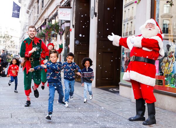 كريسماس الأب، الجنيان والأطفال يقفون لالتقاط صورة خارج متجر ألعاب هامليز، بعد إعلانهم عن أفضل عشر ألعاب لعيد الميلاد المجيد في لندن، بريطانيا، 14 أكتوبر 2021. - سبوتنيك عربي