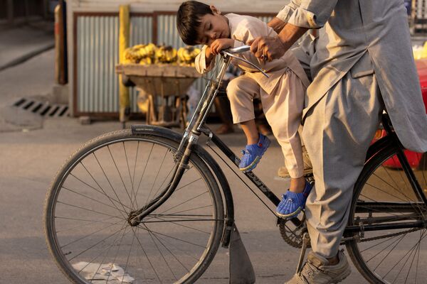 صبي نائم أثناء ركوبه دراجة في كابول، أفغانستان، 18 أكتوبر 2021. - سبوتنيك عربي