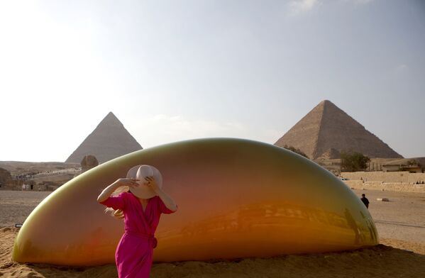 سائحة تسير بجانب تركيب فني، للفنانة الأمريكية جيزيلا كولون، في منطقة الأهرامات في الجيزة، مصر 23 أكتوبر 2021. - سبوتنيك عربي