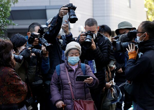 يلتقط مصورون صورًا لامرأة تشاهد بثًا مباشرًا للمؤتمر الصحفي للأميرة اليابانية ماكو وزوجها كي كومورو على هاتفها الذكي، خارج فندق الذي يقام فيه المؤتمر الصحفي لهما في طوكيو، اليابان، 26 أكتوبر 2021. - سبوتنيك عربي