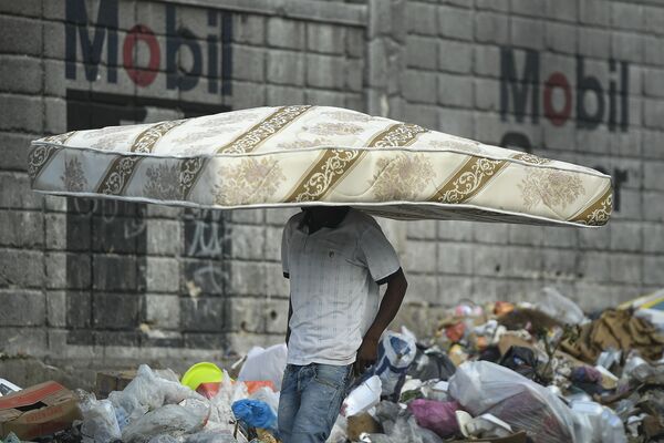 رجل يسير مع فراش على رأسه في بورت أو برنس، هايتي 27 أكتوبر 2021. - سبوتنيك عربي