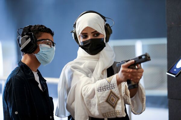 مدربة الأسلحة النارية السعودية، منى الخريص، تعلّم فتى سعوديًا الاستخدام الآمن للأسلحة في ميدان الرماية Top-Gun في الرياض، المملكة العربية السعودية، 28 أكتوبر 2021 - سبوتنيك عربي