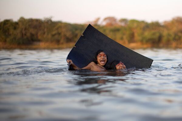 أطفال من قبيلة ياوالابيتي (Yawalapiti) يسبحون في مياه نهر خلال كواروب (Kuarup)، وهي طقوس جنائزية لتكريم ذكرى Cacique Aritana ، زعيم ياوالابيتي، في حديقة شينغو الوطنية، البرازيل، 10 سبتمبر 2021. - سبوتنيك عربي