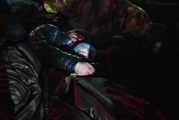 لاجئ من الشرق الأوسط وطفله ينامان على الارض بالقرب من نقطة تفتيش في بروزجي على الحدود البيلاروسية البولندية، 15 نوفمبر 2021 - سبوتنيك عربي