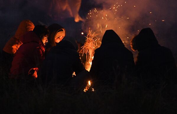 لاجئون من الشرق الأوسط يدفئون أنفسهم بالنار في نقطة تفتيش في بروزجي على الحدود البيلاروسية البولندية. في 8 نوفمبر 2021 - سبوتنيك عربي
