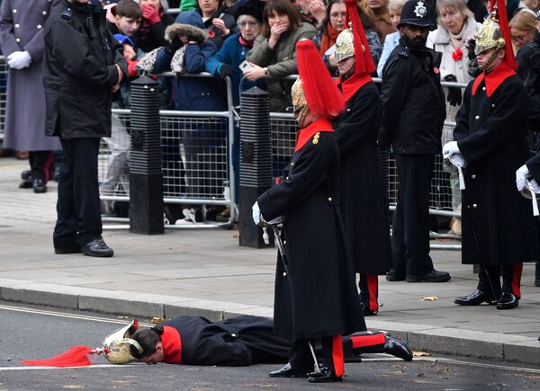 أحد أفراد حرس القصر الملكي البريطاني، يغمى عليه ويرقد على الأرض قبل بدء مراسم إحياء ذكرى يوم الأحد في النصب التذكاري في وايتهول بوسط لندن، بريطانيا 14 نوفمبر 2021. - سبوتنيك عربي
