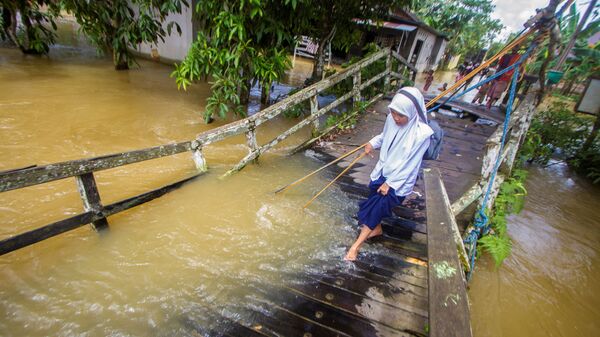طالبة تحاول السير على جسر مكسور، الذي تعرض لمجرى فيضان النهر في قرية جارانيه، وسط هولو سونغاي، مقاطعة كاليمانتان الجنوبية، إندونيسيا، 17 نوفمبر 2021 - سبوتنيك عربي