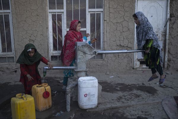 فتيات يملأن حاويات بالمياه باستخدام مضخة يدوية في مخيم للنازحين في كابول، أفغانستان، 15 نوفمبر 2021. - سبوتنيك عربي
