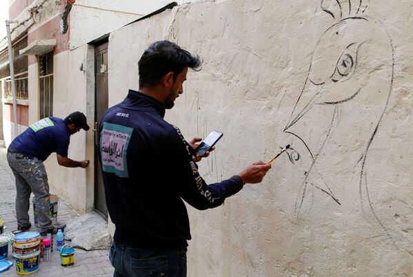 فنان عراقي متطوع يرسم على جدار منزل ضمن فعالية تزيين الحي القديم في الكاظمية في بغداد، العراق، 30 نوفمبر 2021 - سبوتنيك عربي