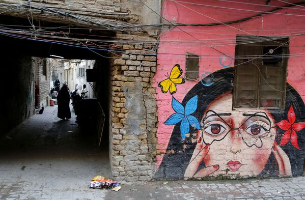 صورة تظهر لوحة جدارية رسمتها مجموعة من الرسامين العراقيين الذين تطوعوا لطلاء جدران منازل الأحياء القديمة لتزيين مدينتهم في حي الكاظمية في بغداد، العراق، 30 نوفمبر 2021 - سبوتنيك عربي