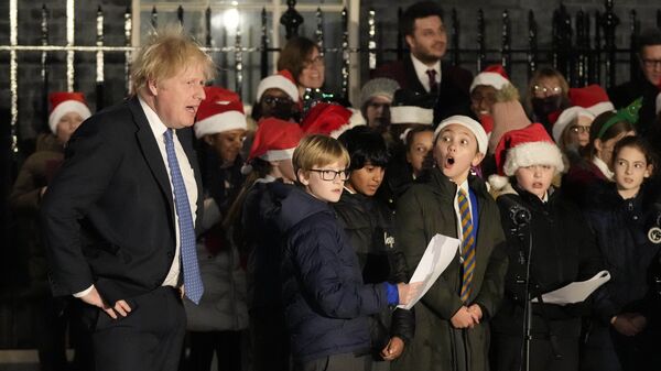 رئيس الوزراء البريطاني بوريس جونسون يستمع إلى جوقة للأطفال تغني خلال الحفل لتشغيل أضواء شجرة عيد الميلاد في داونينج ستريت في لندن، إنجلترا 1 ديسمبر 2021 - سبوتنيك عربي