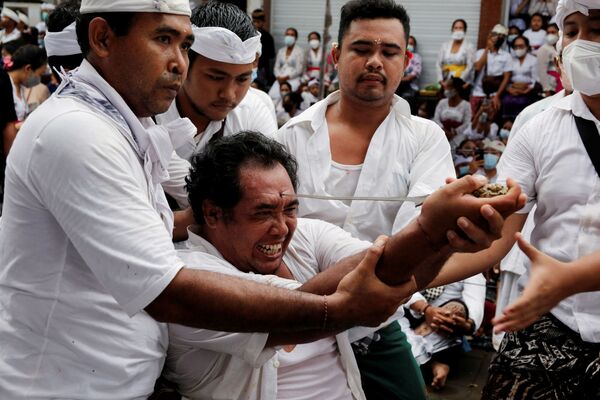 يحاول رجل هندوسي بالي طعن جبهته بخنجر كيريس التقليدي خلال طقوس تسمى نجيريبونغ المقدسة في بالي، إندونيسيا، 28 نوفمبر 2021 - سبوتنيك عربي