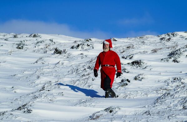 رجل يرتدي زي سانتا (بابا نويل) يمشي في منطقة مغطاة بالثلوج في جلينشي، اسكتلندا، 5 ديسمبر 2021 - سبوتنيك عربي