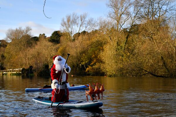 شخص يرتدي زي سانتا (بابا نويل) على متن زورق تجديف أسفل نهر ليفي، لنشر أجواء عيد الميلاد المرحة في ظل استمرار تفشي  وباء كورونا (كوفيد-19) الكئيب، في وسط مدينة دبلن، أيرلندا، 5 ديسمبر 2021 - سبوتنيك عربي