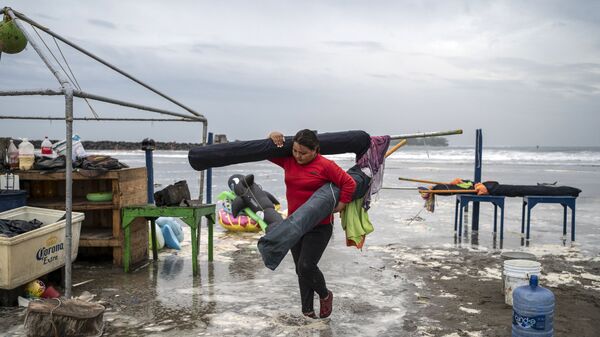 امرأة تزيل المظلات من الشاطئ مع وصول الأمواج القوية إلى الساحل بسبب إعصار غريس، الذي وصل إلى الفئة الثانية، في بوكا ديل ريو، فيراكروز، المكسيك، 20 أغسطس 2021. - سبوتنيك عربي