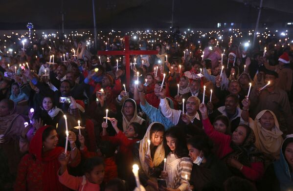 مسيحيون باكستانيون يحملون الشموع خلال احتفال بعيد الميلاد، في لاهور، باكستان، 22 ديسمبر 2021 - سبوتنيك عربي