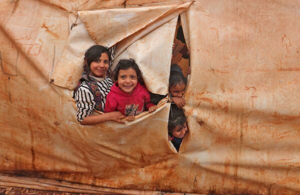 أطفال يحضرون فصلًا في فصول دراسية مؤقتة في مخيم للنازحين من قرية كيلي، بالقرب من باب الهوى على الحدود مع تركيا، في محافظة إدلب شمال غرب سوريا، 20 ديسمبر 2021. - سبوتنيك عربي