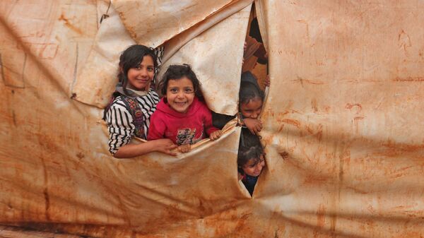 أطفال يحضرون فصلًا في فصول دراسية مؤقتة في مخيم للنازحين من قرية كيلي، بالقرب من باب الهوى على الحدود مع تركيا، في محافظة إدلب شمال غرب سوريا، 20 ديسمبر 2021. - سبوتنيك عربي