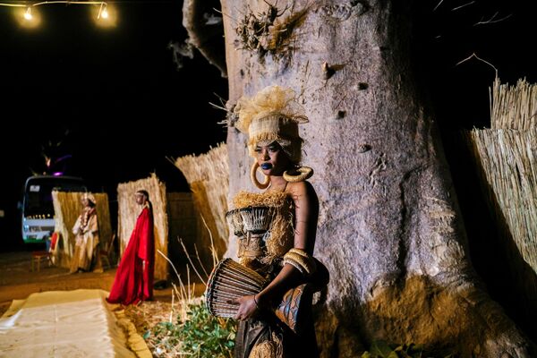 مضيفة تقف على هامش عروض الأزياء خلال أسبوع الموضة التاسع عشر في داكار الذي أقيم في غابة الباوباب في نجكوك، على بعد حوالي 70 كيلومترًا جنوب داكار، 18 ديسمبر 2021. - سبوتنيك عربي