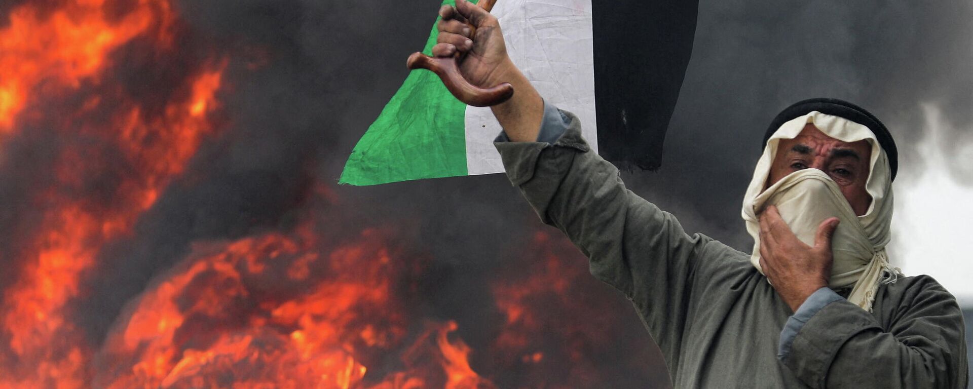 متظاهر فلسطيني يرفع علم فلسطين أمام حاجز من الإطارات المشتعلة في البرقة، الضفة الغربية المحتلة، 23 ديسمبر 2021 - سبوتنيك عربي, 1920, 01.01.2022