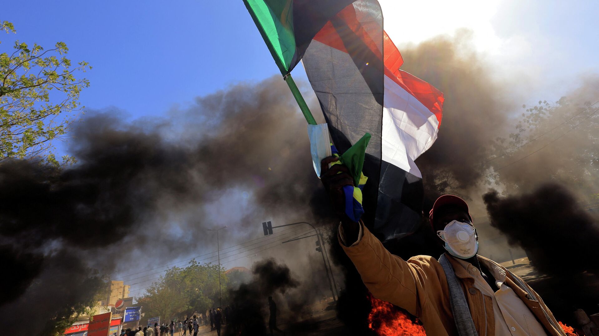 متظاهر في السودان يرفع علم بلاده أثناء احتجاجات الجمعة 31 ديسمبر  - سبوتنيك عربي, 1920, 11.01.2022