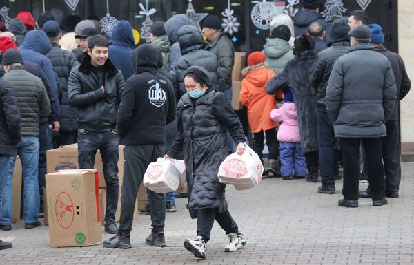 امرأة تحمل أكياسًا بلاستيكية بها خبز بينما يتجمع الناس بالقرب من متجر بعد احتجاجات حاشدة، أثارتها زيادة أسعار الوقود في ألماتي، كازاخستان، 8 يناير 2022. - سبوتنيك عربي