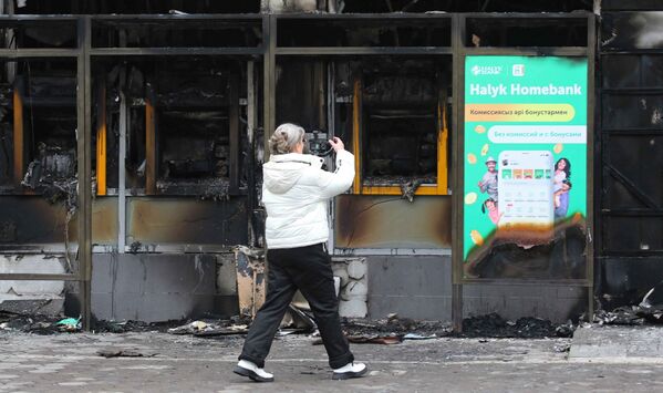 امرأة تصور مبنى تم حرقه خلال احتجاجات حاشدة بسبب زيادة أسعار الوقود، في ألماتي، كازاخستان، 9 يناير 2022. - سبوتنيك عربي